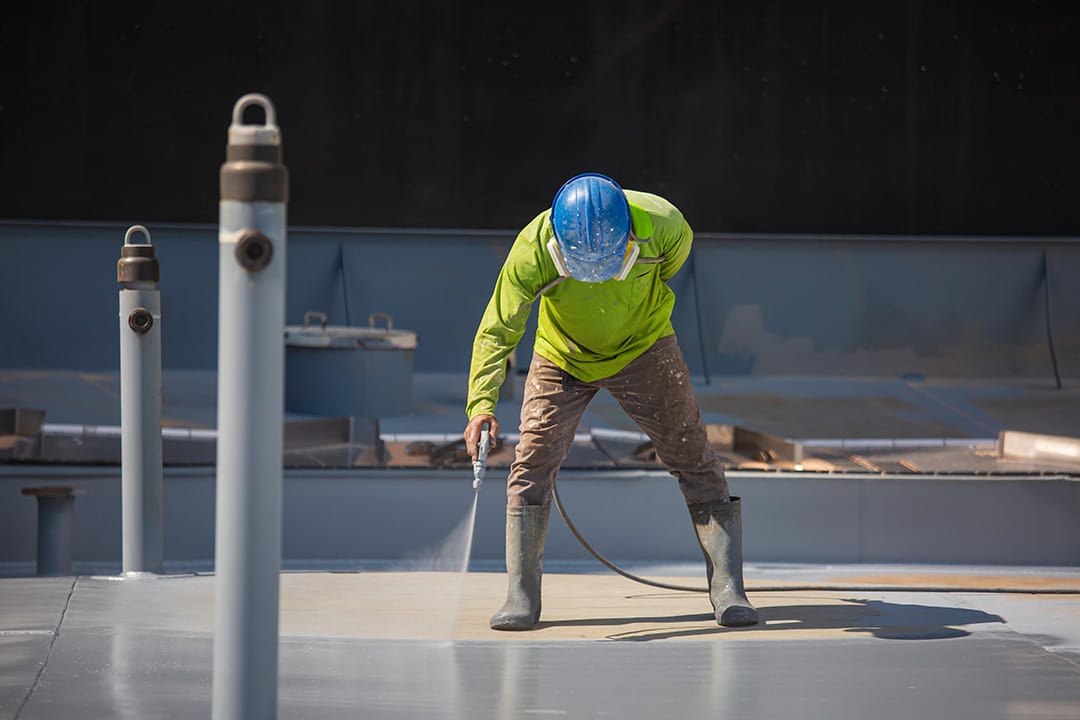 A male worker holding an industrial spray gun used for roof plate tank surface on steel industrial painting and coating.