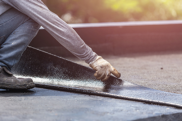 Group of worker installing tar foil on the rooftop of building.