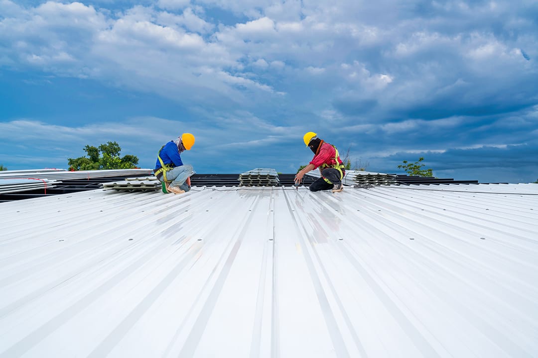 Teamwork of Roofer working at new roof under construction. Safety body construction, Fall arrestor device for worker with hooks for safety body harness on the roof structure.