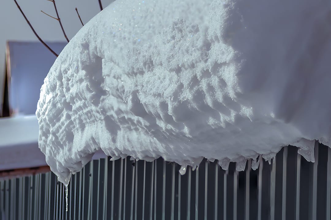 A sea-wave-shaped snowball formed on the edge of the shed roof