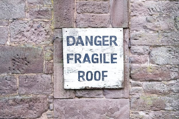 Danger fragile roof sign on wall at farm house