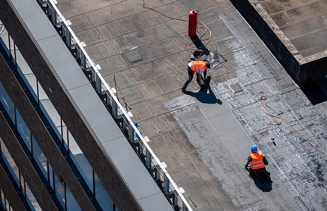 Birds eye view of a roof construction site. Professional bitumen waterproofing on a flat building. Commercial roofing materials.