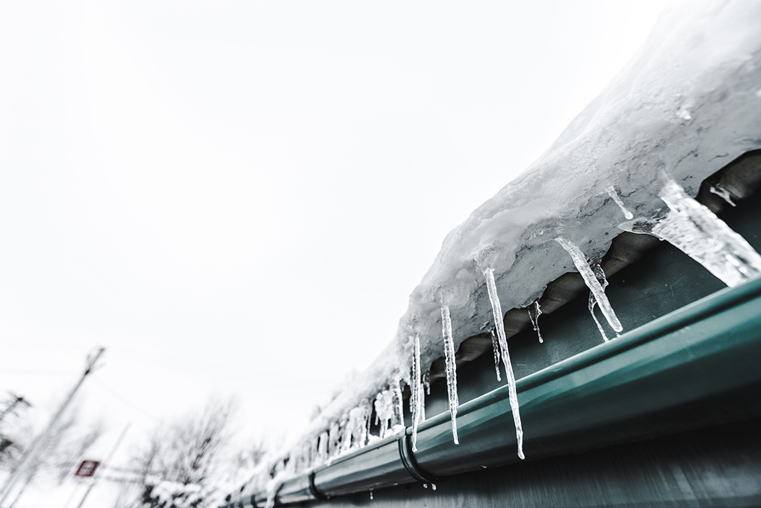 selective focus of sharp icicles on commercial roof against clear sky