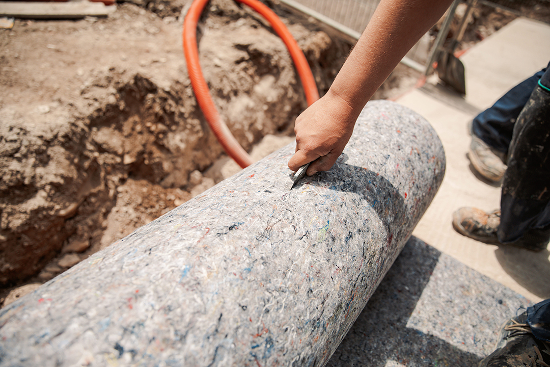 Worker prepares geotextile for the roof, covers it with synthetic PVC membrane. Commercial Roof Repair.