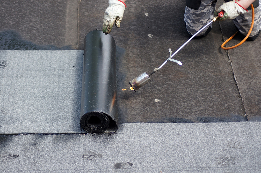 Flat roof installation with propane blowtorch during construction works with roofing felt - Steps of a Flat Roof Replacement