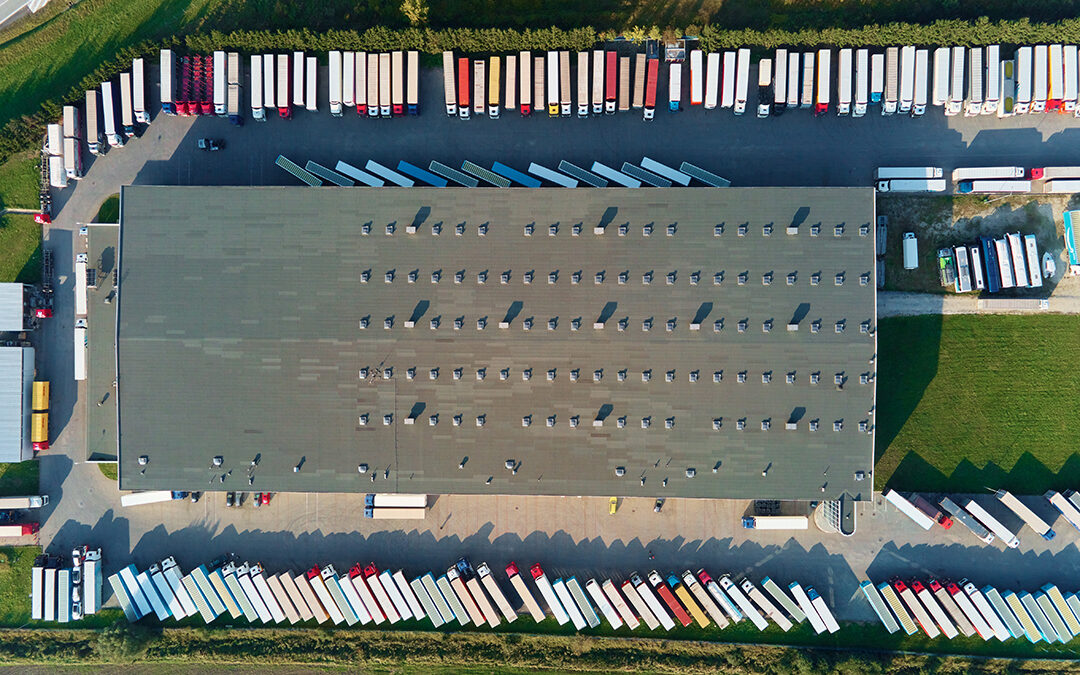 Factory warehouse with parked semi trucks, aerial view