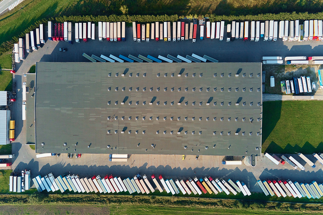 Factory warehouse with parked semi trucks, aerial view